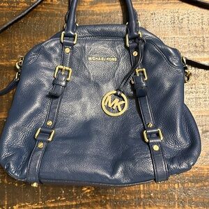 Dark blue Micheal Kors handbag with strap.